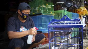 Pedagang memandikan burung di Pasar Barito, Jakarta, Jumat (24/9/2021). [Suara.com/Hilal Rauda Fiqry]