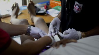 Petugas medis menangani seorang anak yang mengikuti sunatan massal yang digelar di Binong Permai, Kabupaten Tangerang, Banten, Sabtu (25/9/2021). [Suara.com/ Hilal Rauda Fiqry]