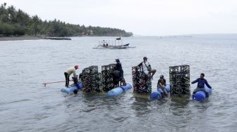 Nelayan membawa apartemen ikan yang akan ditenggelamkan di Pantai Cacalan, Banyuwangi, Jawa Timur, Sabtu (25/9/2021). [ANTARA FOTO/Budi Candra Setya]