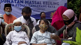 Sejumlah anak didampingi orang tuanya mengantre untuk mengikuti sunatan massal yang digelar di Binong Permai, Kabupaten Tangerang, Banten, Sabtu (25/9/2021). [Suara.com/ Hilal Rauda Fiqry]