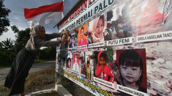 Warga menempelkan bunga pada foto korban bencana gempa dan likuefaksi yang dinyatakan hilang di Kelurahan Petobo, Palu, Sulawesi Tengah, Selasa (28/9/2021). ANTARA FOTO/Mohamad Hamzah
