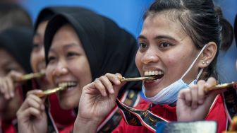 Sejumlah pesepak takraw putri DKI Jakarta menggigit medali emasnya pada upacara pengalungan medali usai pertandingan final ganda putri beregu Sepak Takraw PON Papua melawan Jawa Timur di GOR Trikora Universitas Cenderawasih, Jayapura, Papua, Rabu (29/9/2021).  ANTARA FOTO/M Risyal Hidayat
