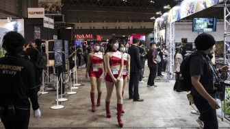 Perempuan penyambut tamu berjalan selama Tokyo Game Show di Prefektur Chiba, Jepang, pada (30/9/2021). [CHARLY TRIBALLEAU / AFP]