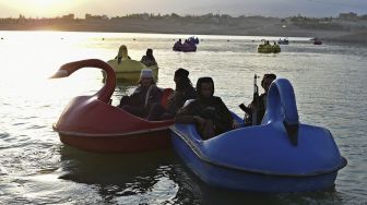 Pejuang Taliban menaiki perahu dayung di sebuah taman bermain di Danau Qargha, Kabul, Afghanistan, pada (28/9/2021). [WAKIL KOHSAR / AFP]