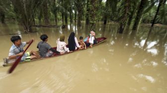 Warga menggunakan perahu keluar dari kepungan banjir di Desa Hagu, Kecamatan Matang Kuli, Aceh Utara, Aceh, Jumat (1/10/2021). [ANTARA FOTO/Rahmad]