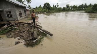 Seorang warga memantau kondisi banjir dari luapan sungai di Desa Blang Priya, Kecamatan Samudera Geudong, Aceh Utara, Aceh, Jumat (1/10/2021). [ANTARA FOTO/Rahmad]