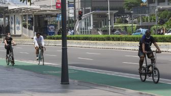 Warga berolahraga di jalan MH. Thamrin, Jakarta Pusat, Minggu (3/10/2021). [Suara.com/Alfian Winanto]