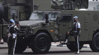 Personel Polisi Militer berfoto di dekat alutsista yang terparkir di depan Istana Merdeka, Jakarta, Senin (4/10/2021). [Suara.com/Angga Budhiyanto]