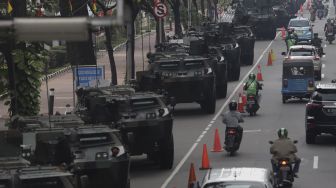 Sejumlah kendaraan melintas di dekat deretan alutsista yang terparkir di kawasan Patung Kuda Arjuna Wiwaha, Jakarta, Senin (4/10/2021). [Suara.com/Angga Budhiyanto]