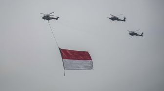 Tiga helikopter TNI terbang dengan mengibarkan bendera Merah Putih di kawasan Monas, Jakarta, Selasa (5/10/2021). ANTARA FOTO/Aprillio Akbar