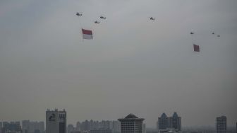 Tujuh helikopter TNI terbang dengan mengibarkan bendera Merah Putih dan Lambang TNI di kawasan Monas, Jakarta, Selasa (5/10/2021). ANTARA FOTO/Aprillio Akbar