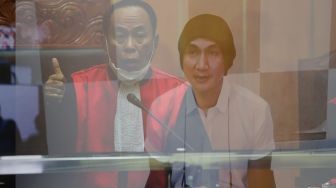 Foto Double Eksposure Musisi Erdian Aji Prihartanto atau Anji saat menjalani sidang secara virtual di Pengadilan Negeri Jakart Barat, Rabu (6/10/2021). [Suara.com/Alfian Winanto]
