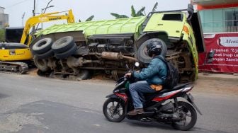 Sejumlah pengendara roda dua melintas di samping truk yang terperosok galian pipa PDAM di jalan raya Legok, Kabupaten Tangerang, Banten, Kamis (7/10).  [Suara.com/ Hilal Rauda Fiqry] 