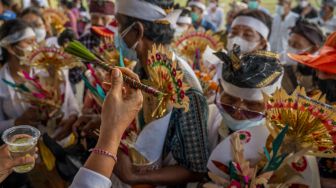 Petugas memercikkan air suci saat ritual Ngeplugin (pemandian roh) pada upacara Ngaben Ngerit di Pura Prajapati, Palu, Sulawesi Tengah, Kamis (7/10/2021). [ANTARA FOTO/Basri Marzuki]