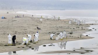 Kru pembersihan bekerja di Pantai Newport, California, pada (7/10/2021). [Frederic J. BROWN / AFP]