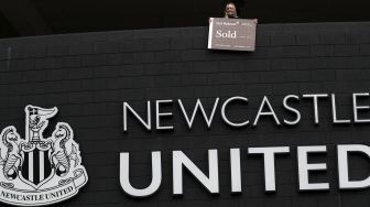 Seorang pendukung Newcastle United memegang tanda 'Terjual' di atas logo klub di St James 'Park, Newcastle upon Tyne, Inggris, pada (7/10/2021). [AFP]