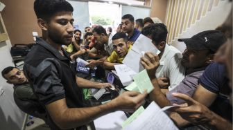 Warga Palestina berkumpul untuk mengajukan izin kerja di Israel, di kamp pengungsi Jabalia, Jalur Gaza, pada (6/10/2021). [Mahmud hams / AFP]