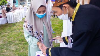 Petugas TPS memberikan tinta ke jari warga setelah melakukan pencoblosan di TPS 04 Desa Bojong Kamal, Kabupaten Tangerang, Banten, Minggu 10/10. ( Suara.com/ Hilal Rauda Fiqry) 