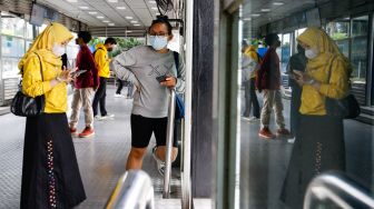 Penumpang mengisi saldo kartu JakLingko di Halte Bundaran HI, Jakarta Pusat, Minggu (10/10/2021). [Suara.com/Alfian Winanto]