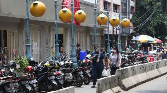Pejalan kaki melintas di kawasan Glodok, Jakarta Barat, Minggu (10/10/2021). [Suara.com/Alfian Winanto]