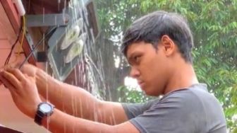 Di Bawah Guyuran Hujan, Pria Ini Fokus Kerja Tanpa Basah, Warganet: Abangnya Waterproof