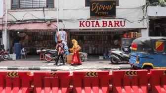 Pejalan kaki melintas di kawasan Glodok, Jakarta Barat, Minggu (10/10/2021). [Suara.com/Alfian Winanto]