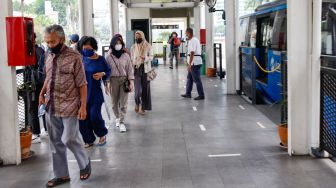 Penumpang beraktivitas di Halte Bundaran HI, Jakarta Pusat, Minggu (10/10/2021). [Suara.com/Alfian Winanto]