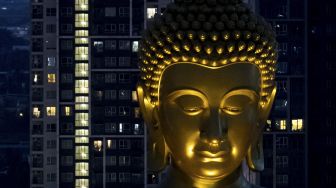 Patung Buddha raksasa setinggi 69 meter berdiri di kuil Wat Paknam Phasi Charoen, Bangkok, pada (12/10/2021). [JACK TAYLOR / AFP]