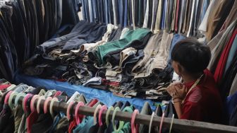 Seorang pedagang pakaian bekas layak pakai (thrifting) menunggu pembeli di Pasar Kebayoran Lama, Jakarta, Rabu (13/10/2021). [Suara.com/Angga Budhiyanto]