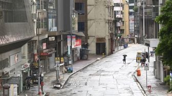 Seorang pejalan kaki melintasi jalan yang kosong di kawasan pusat bisnis di Hong Kong, pada (13/10/2021). [PETER PARKS / AFP]