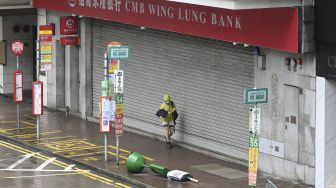 Seorang pejalan kaki melintasi jalan yang kosong di kawasan pusat bisnis di Hong Kong, pada (13/10/2021). [PETER PARKS / AFP]