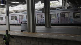 Petugas berjalan melintasi gerbong kereta commuter line yang dipasangi tanda kampanye inklusif tentang disabilitas yang berhenti di Stasiun Jatinegara, Jakarta, Jumat (15/10/2021). [Suara.com/Angga Budhiyanto]