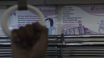 Tanda kampanye inklusif tentang disabilitas terpasang di salah satu gerbong kereta commuter line yang berhenti di Stasiun Jatinegara, Jakarta, Jumat (15/10/2021). [Suara.com/Angga Budhiyanto]