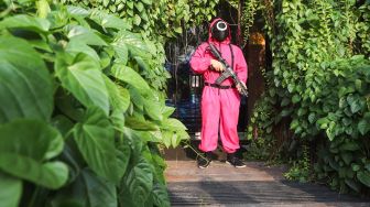 Pramusaji yang menggunakan kostum dari film Squid Game menunggu pengunjung di pintu masuk di Strawberry Cafe, Jakarta Barat, Sabtu (16/10/2021). [Suara.com/Alfian Winanto]