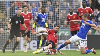 Bek Leicester City Timothy Castagne (kanan) menjegal gelandang Manchester United Bruno Fernandes (tengah) selama pertandingan sepak bola Liga Premier Inggris antara Leicester City dan Manchester United di King Power Stadium, Leicester, Inggris pada (16/10/2021). [PAUL ELLIS / AFP]