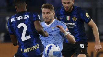 Bek Inter Milan Denzel Dumfries (kiri) bersama bek Inter Milan Stefan de Vrij (kanan) berebut bola dengan penyerang Lazio Ciro Immobile selama pertandingan sepak bola Serie A Italia antara Lazio dan Inter di stadion Olimpiade, Roma, pada (16/10/2021). [FILIPPO MONTEFORTE / AFP]