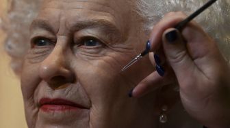 Seniman studio Emma Meehan memberikan sentuhan akhir pada patung lilin baru Ratu Elizabeth II Inggris di Madame Tussauds, Blackpool, Inggris, pada (14/10/2021). [PAUL ELLIS / AFP]