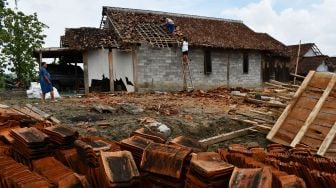 Warga membenahi atap rumah yang rusak di dekat rumah roboh akibat puting beliung di Desa Sumberbendo, Saradan, Kabupaten Madiun, Jawa Timur, Senin (18/10/2021). ANTARA FOTO/Siswowidodo
