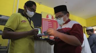 Warga menunjukkan kartu tanda penduduk kepada petugas untuk mendapatkan makanan gratis di Soto Seger Boyolali Hj. Amanah, Lebak Bulus, Jakarta, Selasa (19/10/2021). [Suara.com/Angga Budhiyanto]