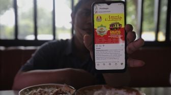 Warga menunjukkan sebaran promo makan gratis melalui gawainya di Soto Seger Boyolali Hj. Amanah, Lebak Bulus, Jakarta, Selasa (19/10/2021). [Suara.com/Angga Budhiyanto]