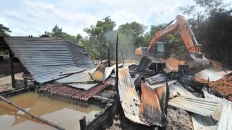 Petugas merobohkan tempat penyulingan minyak mentah ilegal menggunakan alat berat di Jambi Luar Kota, Muarojambi, Jambi, Selasa (19/10/2021). [ANTARA FOTO/Wahdi Septiawan]