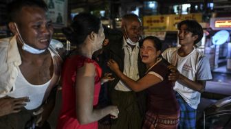 Seorang pria merayakan dengan kerabat setelah dibebaskan dari Penjara Insein, Yangon, Myanmar, pada (19/10/2021). [STR / AFP]