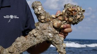 Jacob Sharvit dari Israel Antiquities Authority menunjukkan pedang kuno sepanjang satu meter yang diyakini milik Tentara Salib, di Pelabuhan Israel Kaisarea, pada (19/10/2021). [JACK GUEZ / AFP]