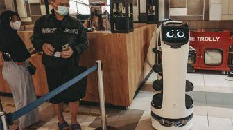 Pengunjung berdiri di samping  Robot pramusaji “Bellabot” di Tangcity Mall, Kota Tangerang, Banten, Kamis (21/10/2021). [Suara.com/ Hilal Rauda Fiqry]