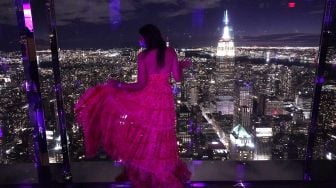 Seorang pengunjung berpose saat anggota media menghadiri press preview untuk mengunjungi 'SUMMIT by Night' menjelang grand opening 'SUMMIT One Vanderbilt' di New York, pada (18/10/2021). [TIMOTHY A. CLARY / AFP]