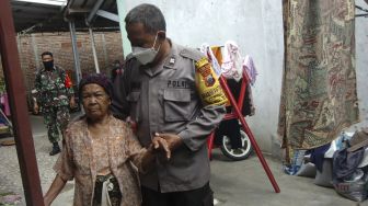 Personel kepolisian menuntun nenek bernama Tarmi usai melakukan penyuntikan di rumahnya Kelurahan Kalinyamat Wetan, Tegal, Jawa Tengah, Kamis (21/10/2021). [ANTARA FOTO/Oky Lukmansyah]