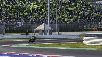 Pembalap Yamaha-SRT Italia Valentino Rossi mengendarai sepeda motornya melewati para penggemarnya selama Grand Prix MotoGP Emilia-Romagna di Sirkuit Dunia Misano Marco-Simoncelli, Misano Adriatico, Italia, pada (24/10/2021). [ANDREAS SOLARO / AFP]