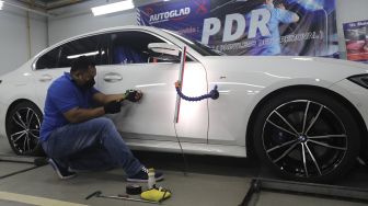 Teknisi melakukan proses perbaikan cat dan bodi mobil BMW saat peresmian Autoglad di Bengkel Autoglad, Jalan Raya Pekayon, Bekasi, Jawa Barat, Kamis (28/10/2021). [Suara.com/Angga Budhiyanto]