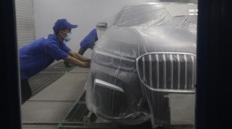 Teknisi melakukan proses perbaikan cat dan bodi mobil BMW saat peresmian Autoglad di Bengkel Autoglad, Jalan Raya Pekayon, Bekasi, Jawa Barat, Kamis (28/10/2021). [Suara.com/Angga Budhiyanto]