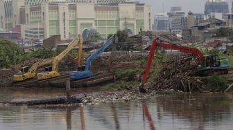 Petugas dari Suku Dinas Sumber Daya Air Jakarta Pusat mengoperasikan alat berat untuk mengangkut sampah di sepanjang aliran Kanal Banjir Barat di kawasan Tanah Abang, Jakarta, Jumat (29/10/2021). [Suara.com/Angga Budhiyanto]